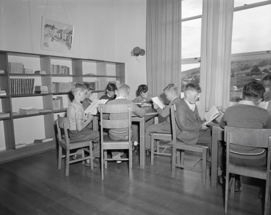 Boys sitting at tables reading books